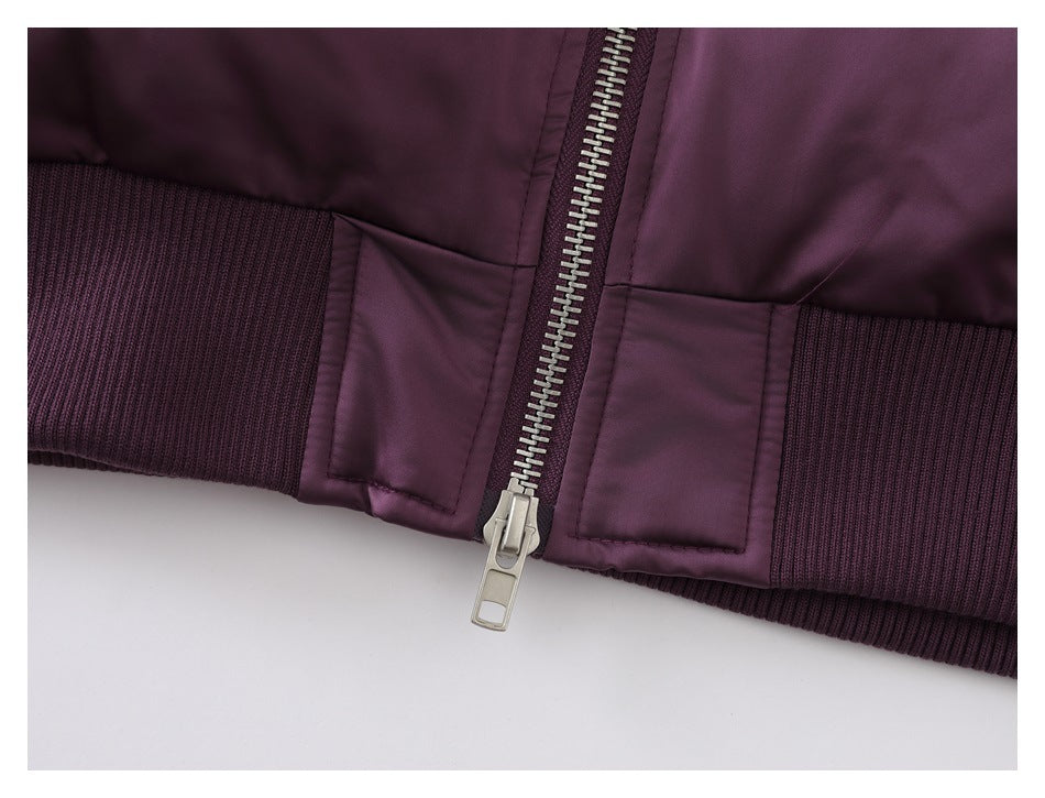 Close-up of a plum-purple jacket's silver front zipper and dark ribbed hem.