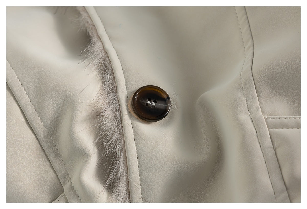 Close-up of an ivory coat with a dark brown button beside a pale faux-fur trim.
