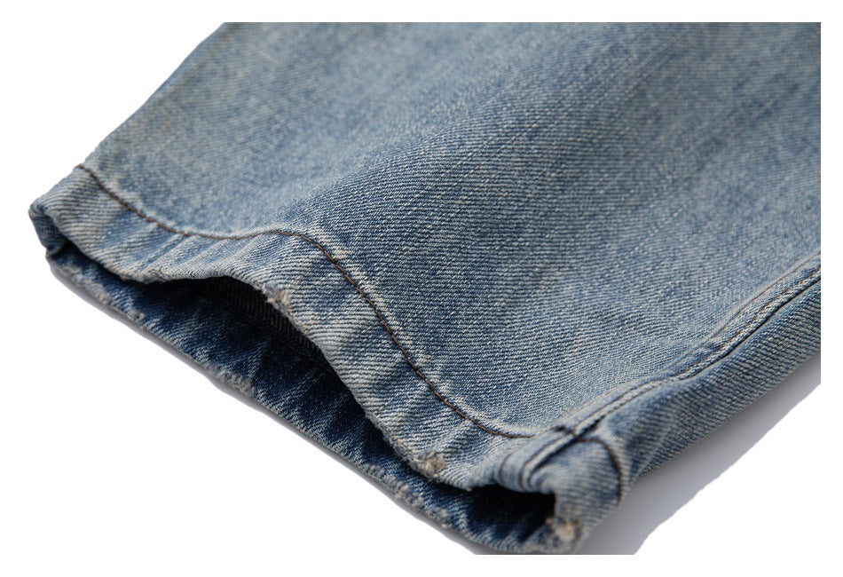 Close-up of the hem of light blue denim jeans with visible stitching.