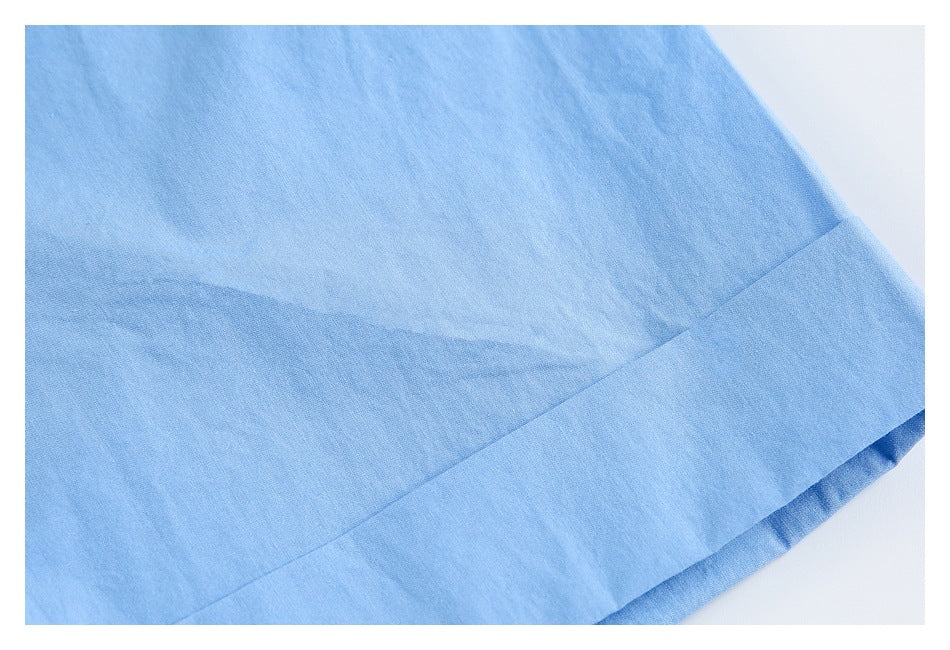 Close-up of light blue garment fabric showing a wide folded, stitched hem.