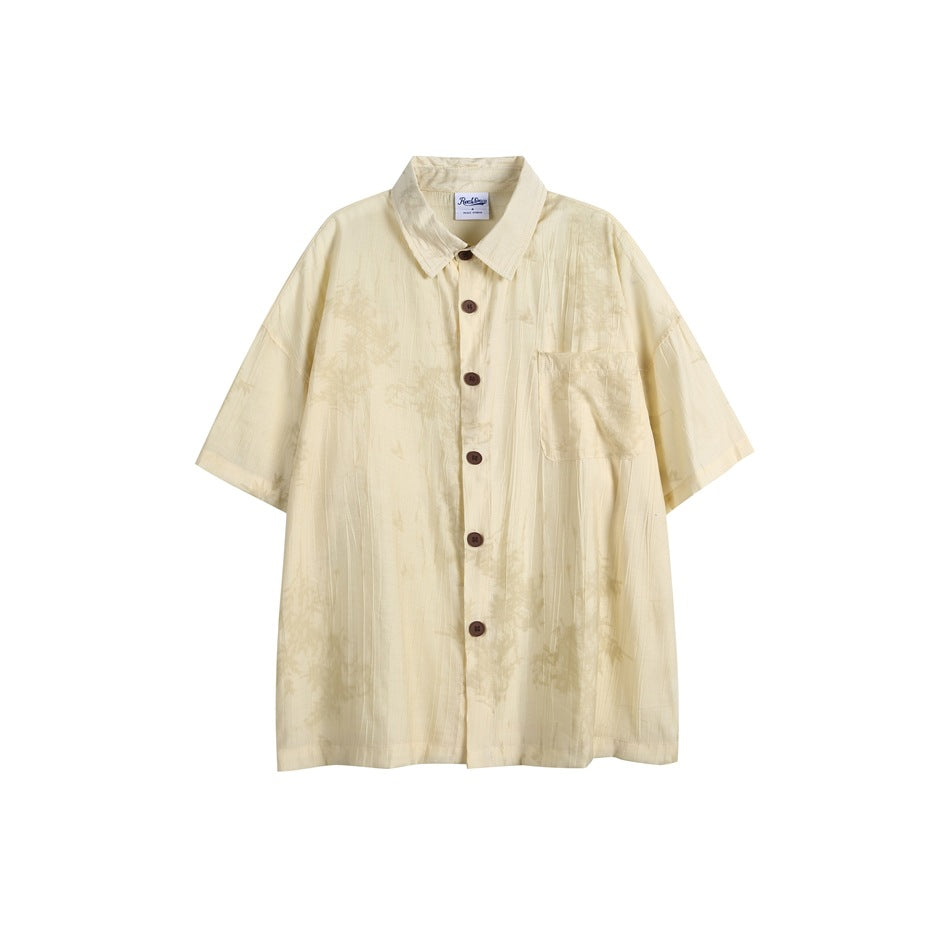 Pale yellow short-sleeve button-up shirt with brown buttons, chest pocket and faint tonal leaf print, flat lay