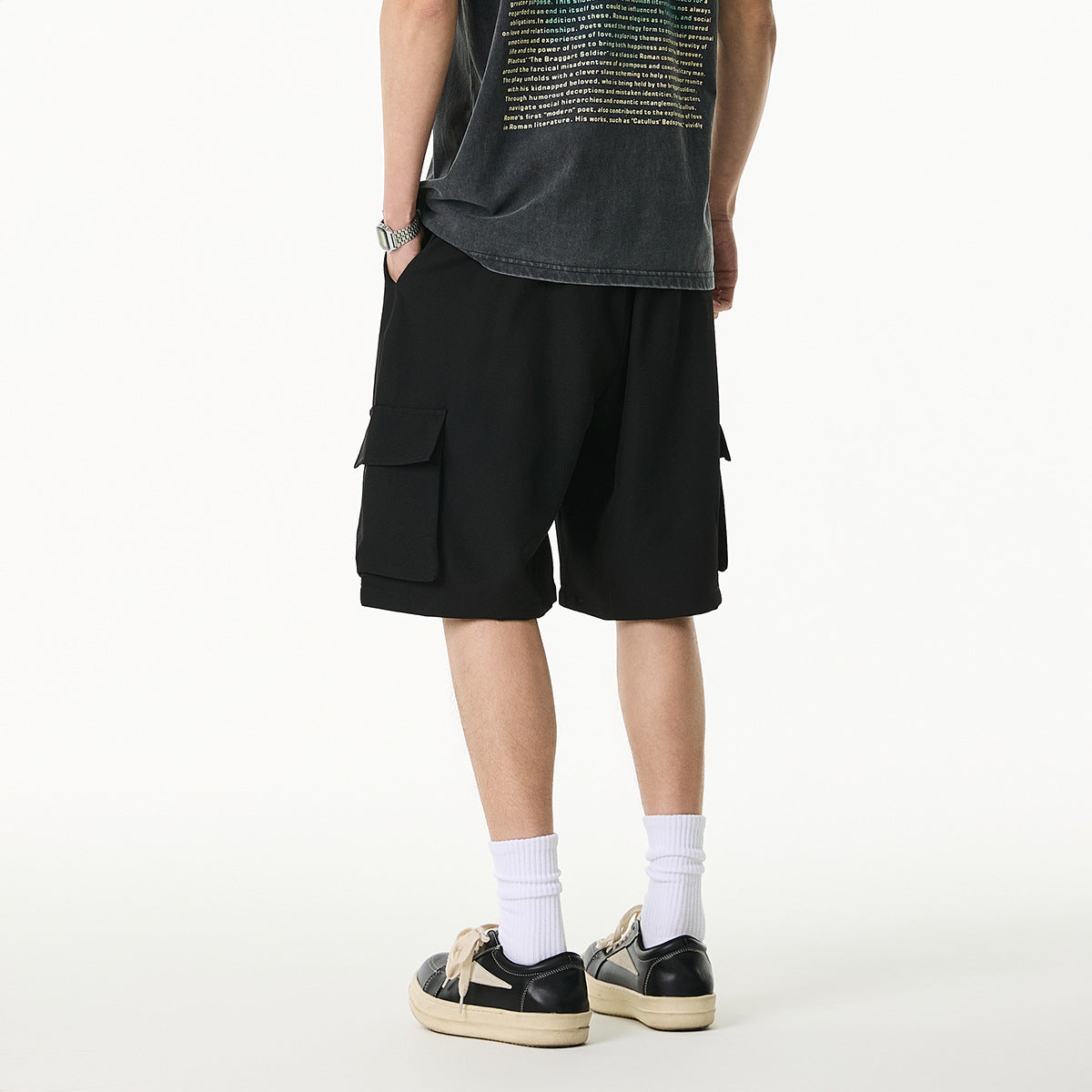 Rear view of a model wearing loose black cargo shorts with flap pockets on both sides.