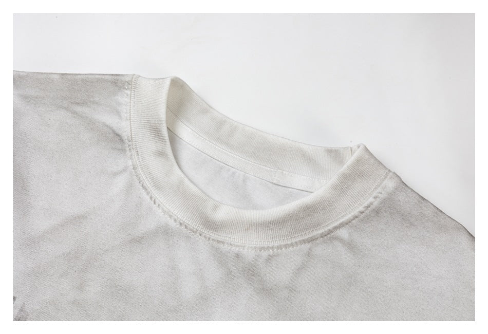 Close-up of an off-white T-shirt's ribbed crew neck and shoulder seams.