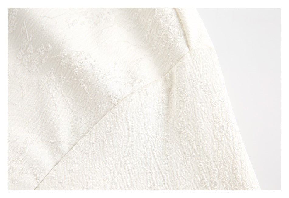 Close-up of ivory textured fabric showing a diagonal seam and stitched panel.