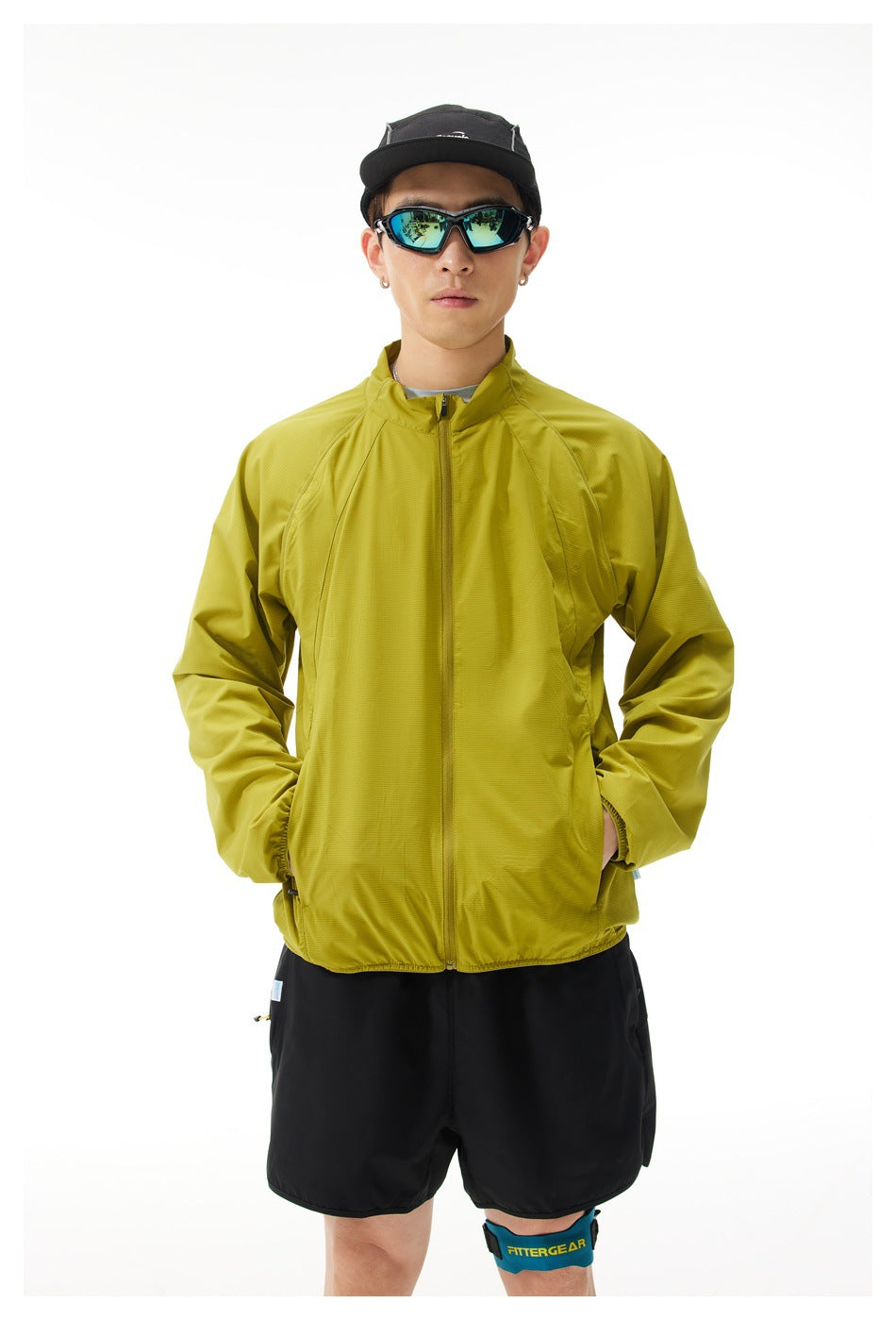 Front view of a model wearing a chartreuse zip jacket and black shorts.