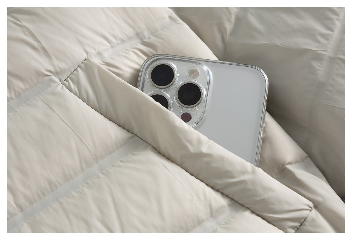 Close-up of a cream quilted puffer jacket with a smartphone partly tucked into a pocket.