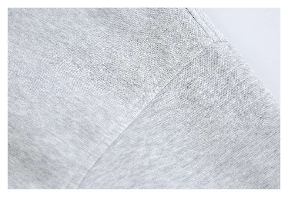 Close-up of stitching and a seam on the shoulder of a light gray hoodie.
