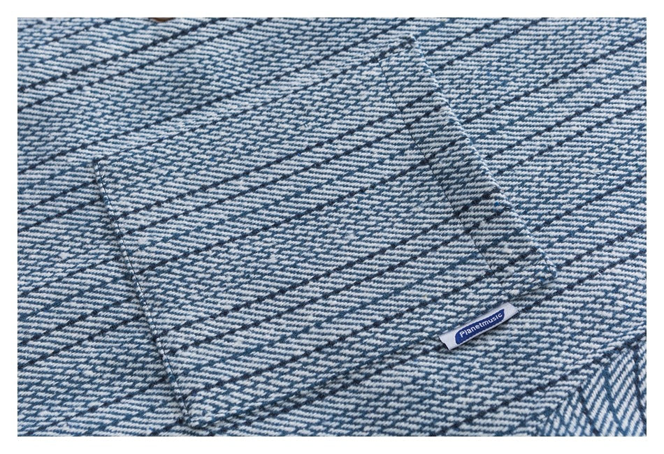 Close-up of blue-and-white patterned fabric with a pocket seam and a small Planetmusic tag.