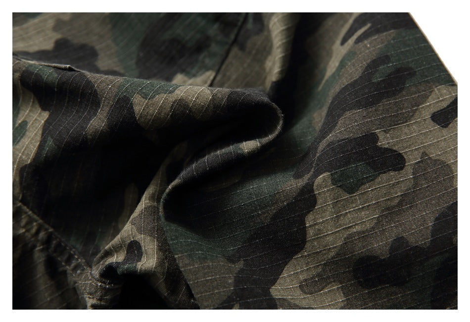 Close-up of folded green, brown, and black camouflage fabric showing its fine horizontal weave.