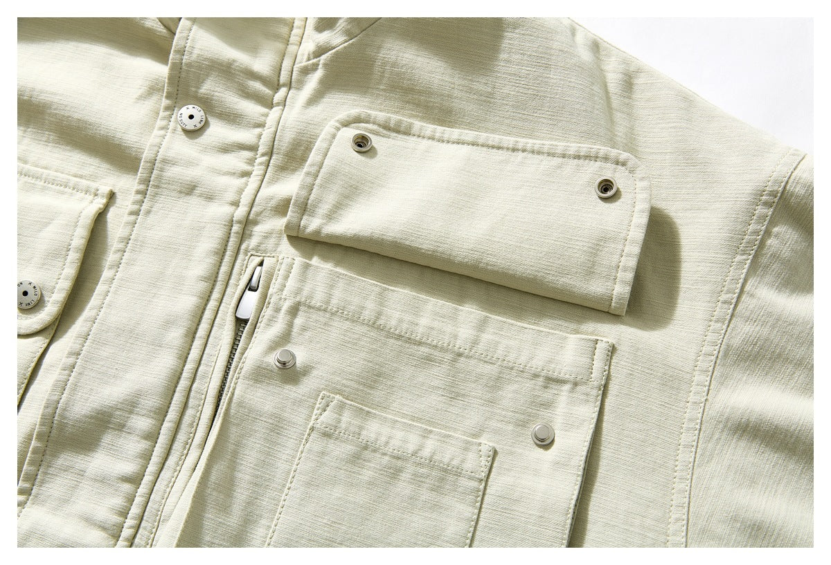 Close-up of a pale beige jacket's snap-fastened flap pocket, lower patch pocket and zipper.