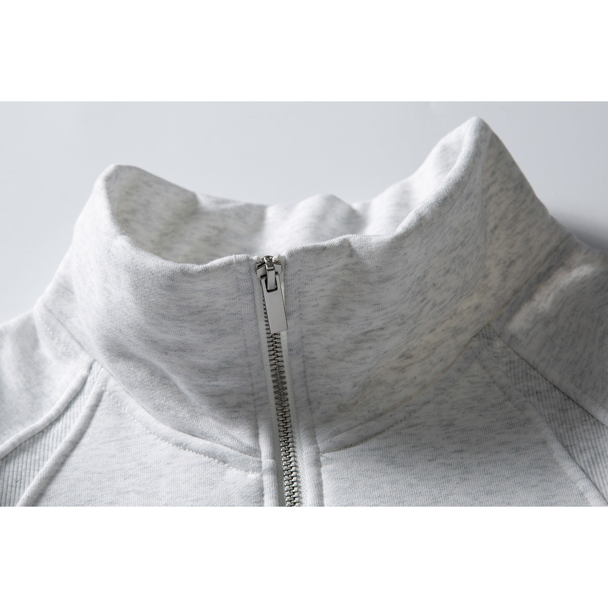 Close-up of a light gray zip-up jacket's tall stand collar and metal zipper.