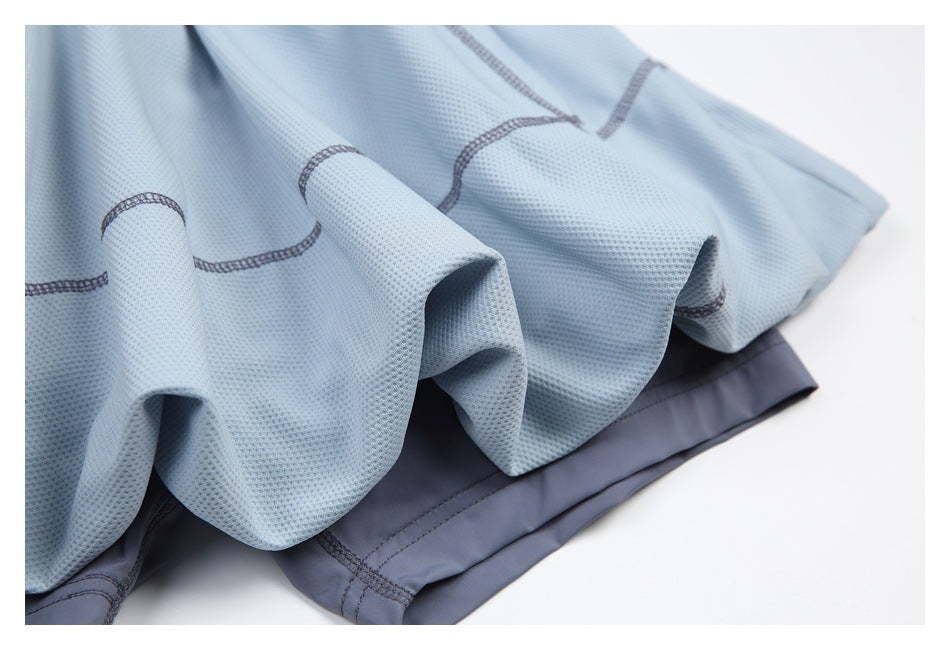 Close-up of gathered light blue textured fabric, dark overlock stitching, and a charcoal-gray edge.