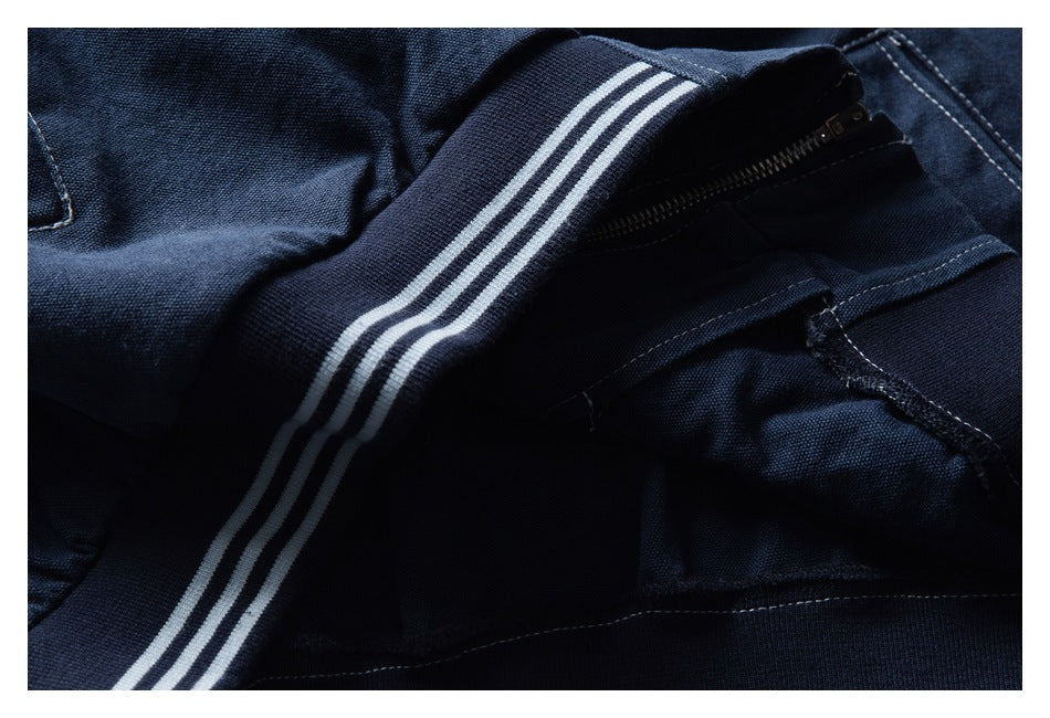Close-up of dark navy fabric, a striped ribbed band, and an open zipper.