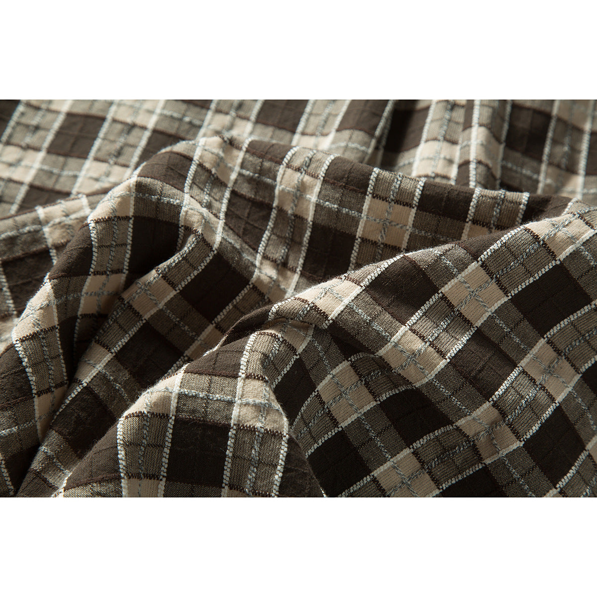 Close-up of brown, beige and gray plaid shirt fabric draped to show its woven texture and folds.