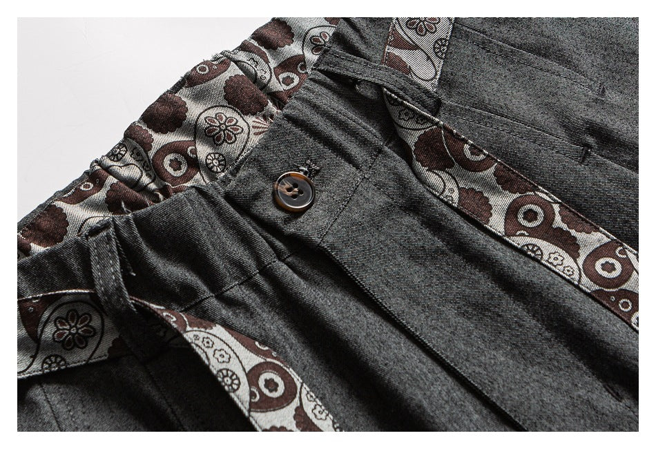 Close-up of charcoal trousers showing the buttoned waist and patterned inner waistband.