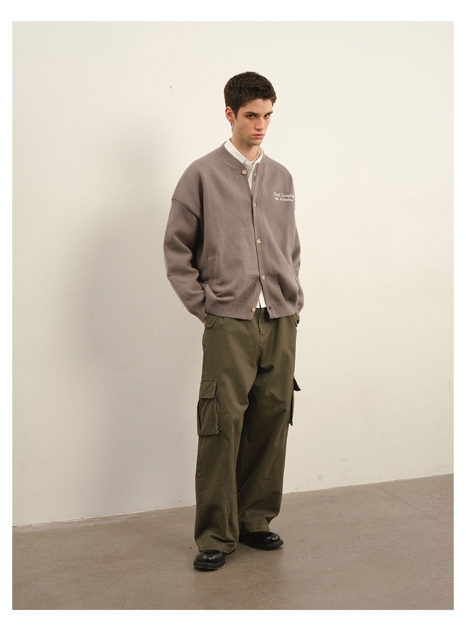 Model wearing a taupe embroidered button cardigan over a white shirt with olive cargo trousers.