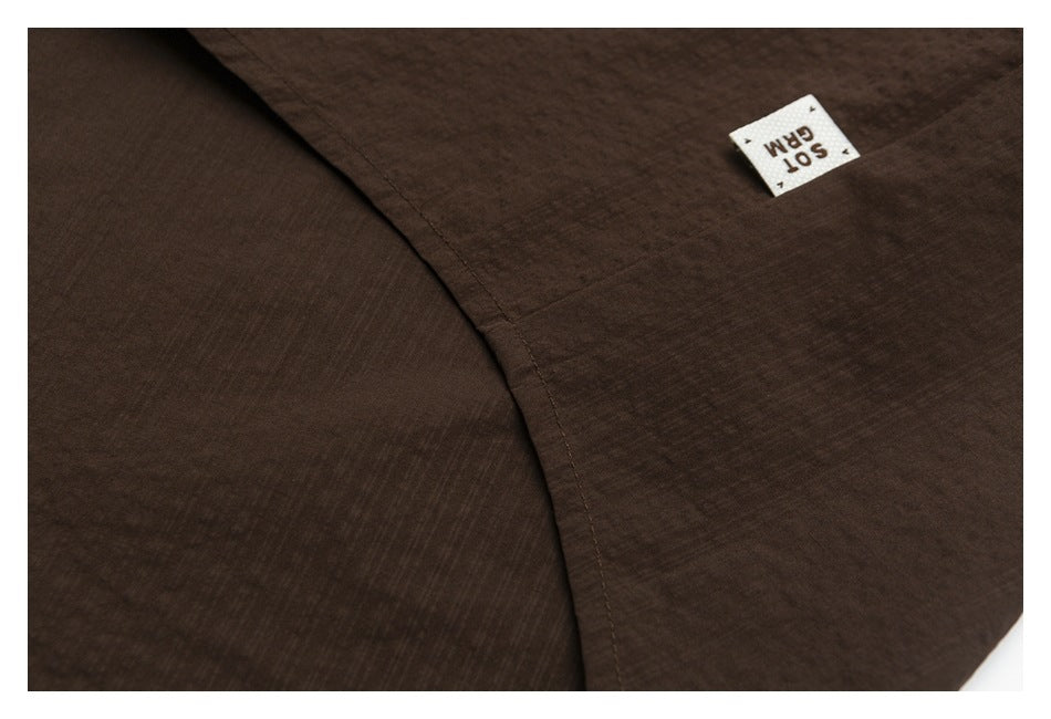 Close-up of dark brown fabric, a curved stitched seam, and a small white sewn-in label.