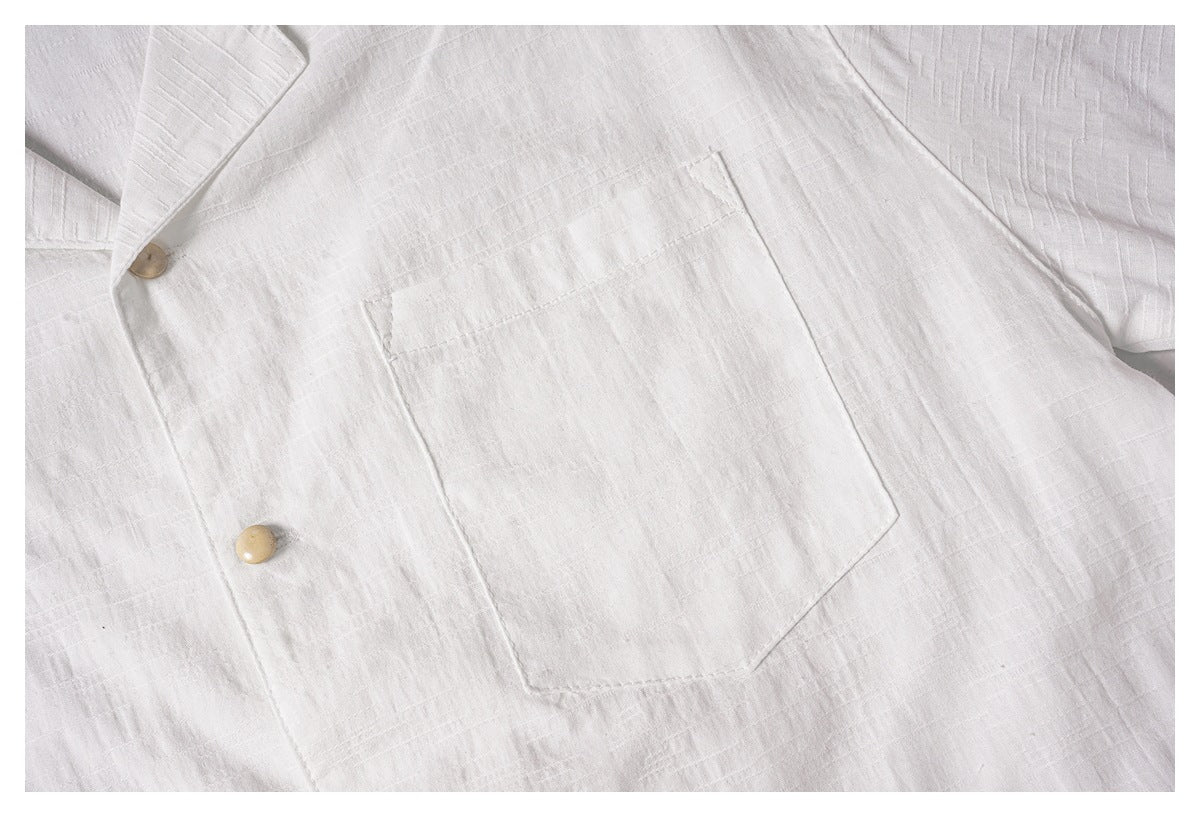 Close-up of the white shirt's large front chest pocket and tan buttons.