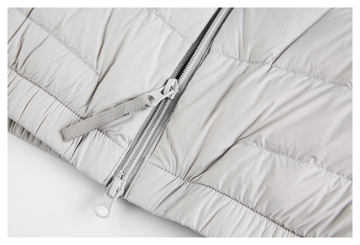 Close-up of a light gray quilted jacket's double zipper and gathered hem.