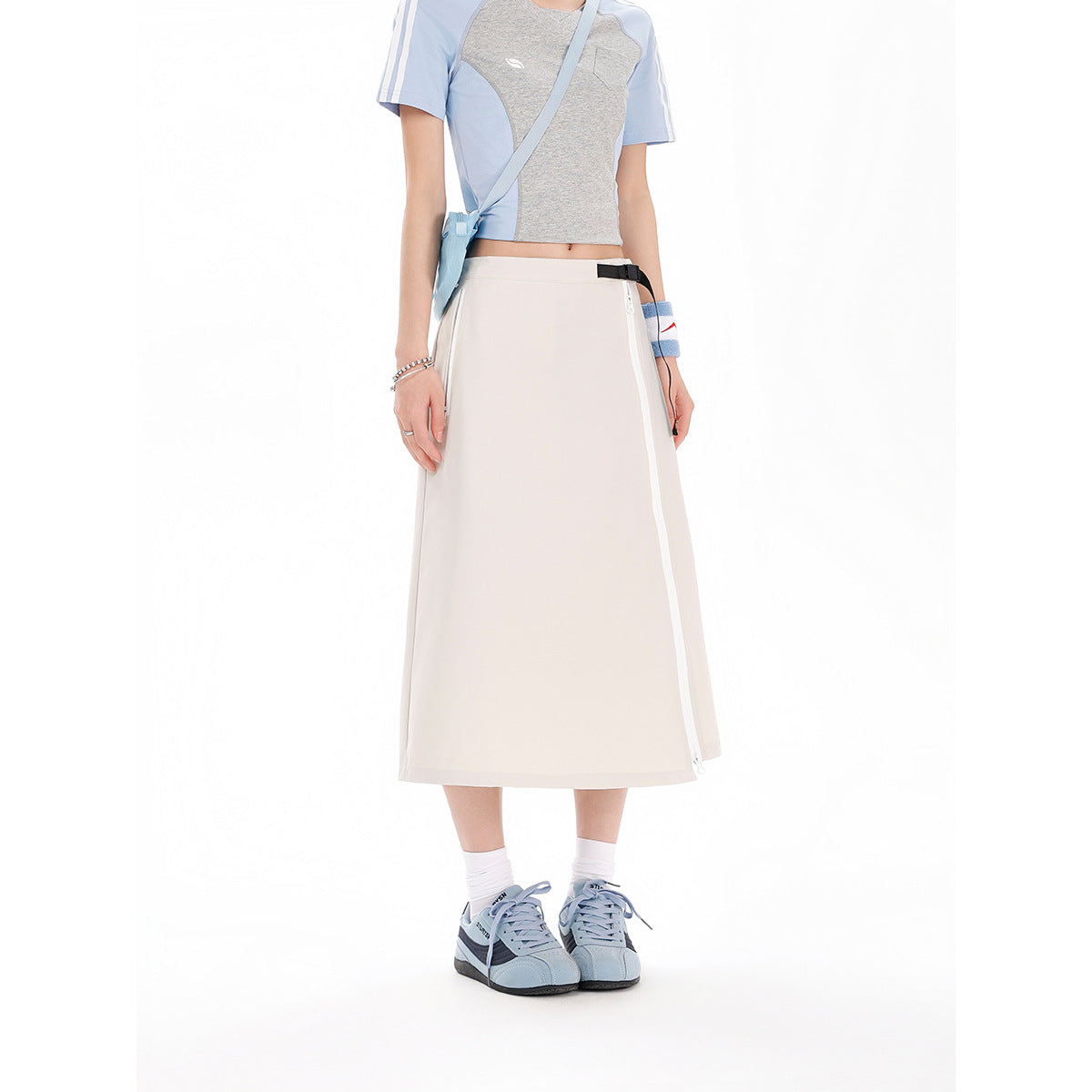 Cropped model wearing a pale ivory A-line midi skirt with a side zipper and black waist buckle.