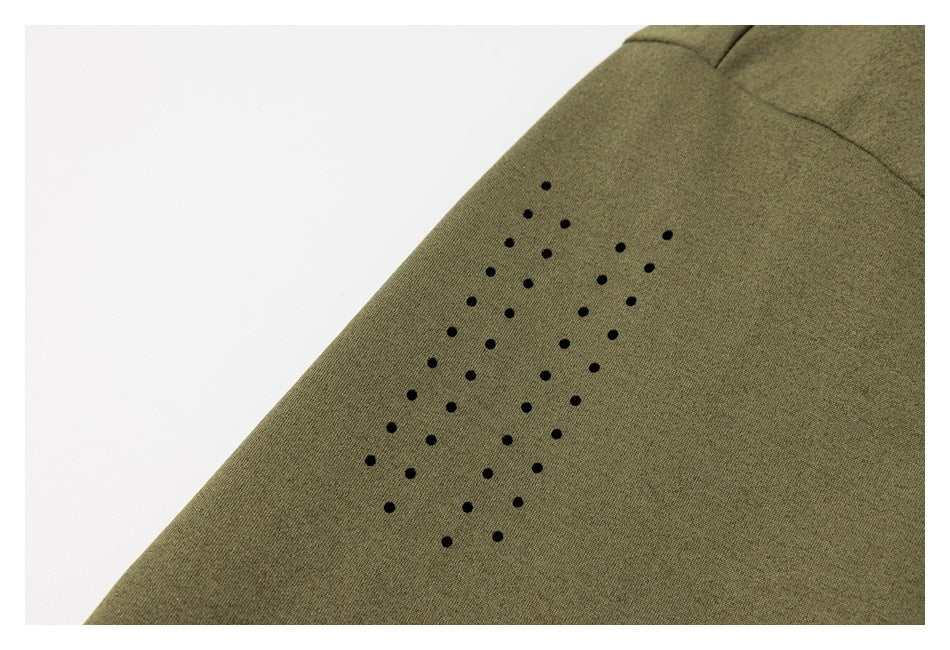 Close-up of an olive-green garment panel with a cluster of black perforations near a seam.