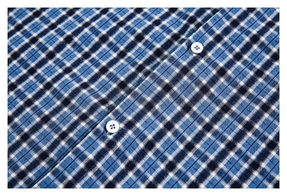 Close-up of the blue, black, and white plaid shirt front with two white buttons.