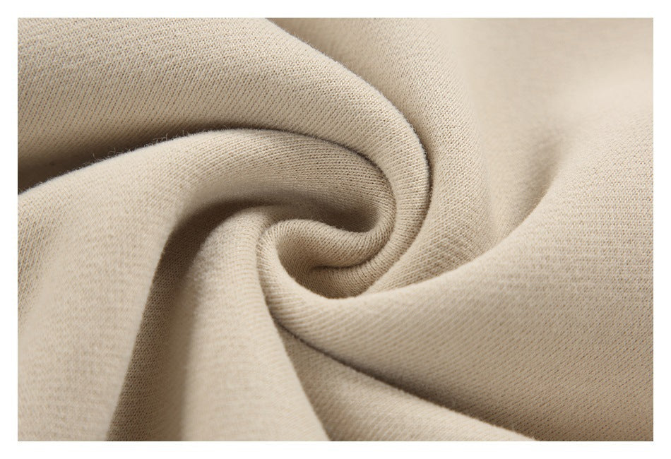 Macro view of beige sweatshirt fabric gathered into folds, showing its knit surface.