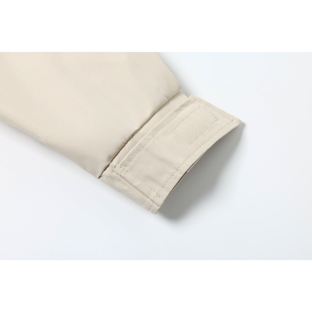 Close-up of the stitched cuff and rectangular detail on a light beige jacket sleeve.