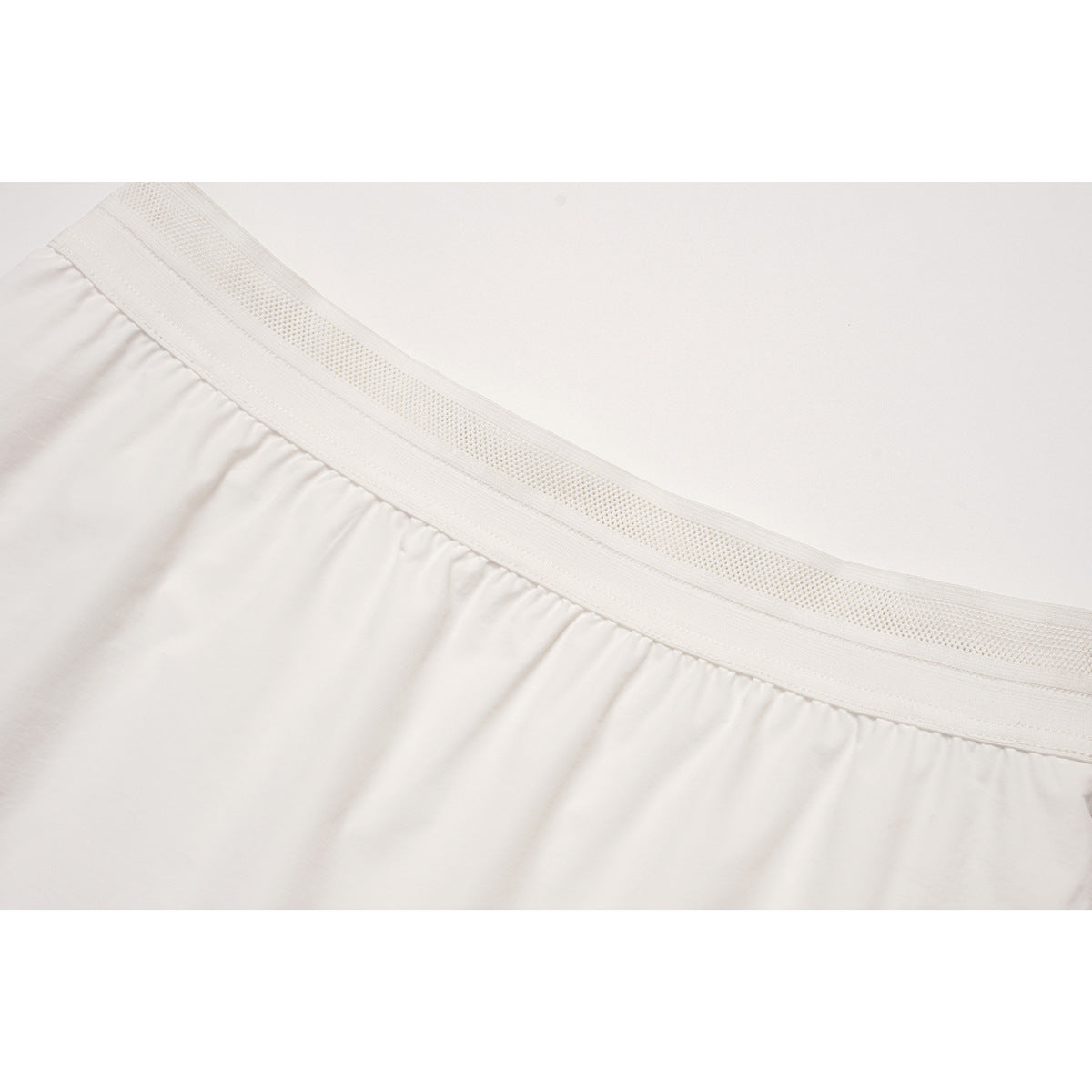 Close-up of a white gathered skirt waistband with a wide perforated elastic band.