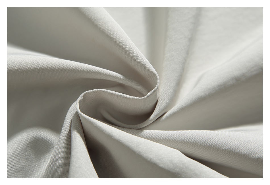 Macro view of light beige fabric draped into soft folds, showing its fine surface texture.
