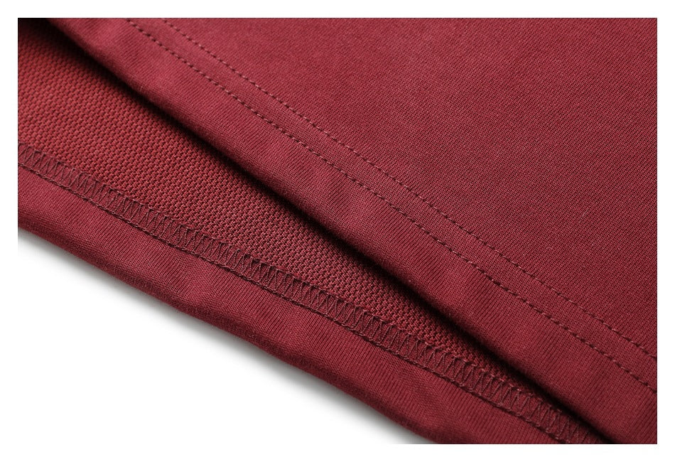 Close-up of burgundy garment fabric showing a folded hem and overlocked stitching.