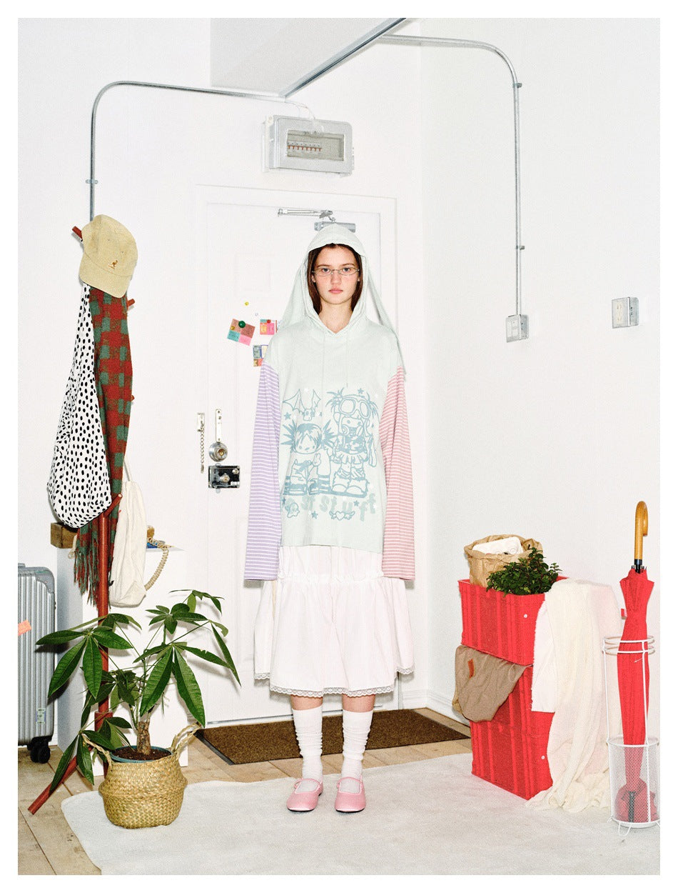 Front view of a person wearing a pale mint bunny-ear hoodie with mismatched pink and lavender striped sleeves and a blue