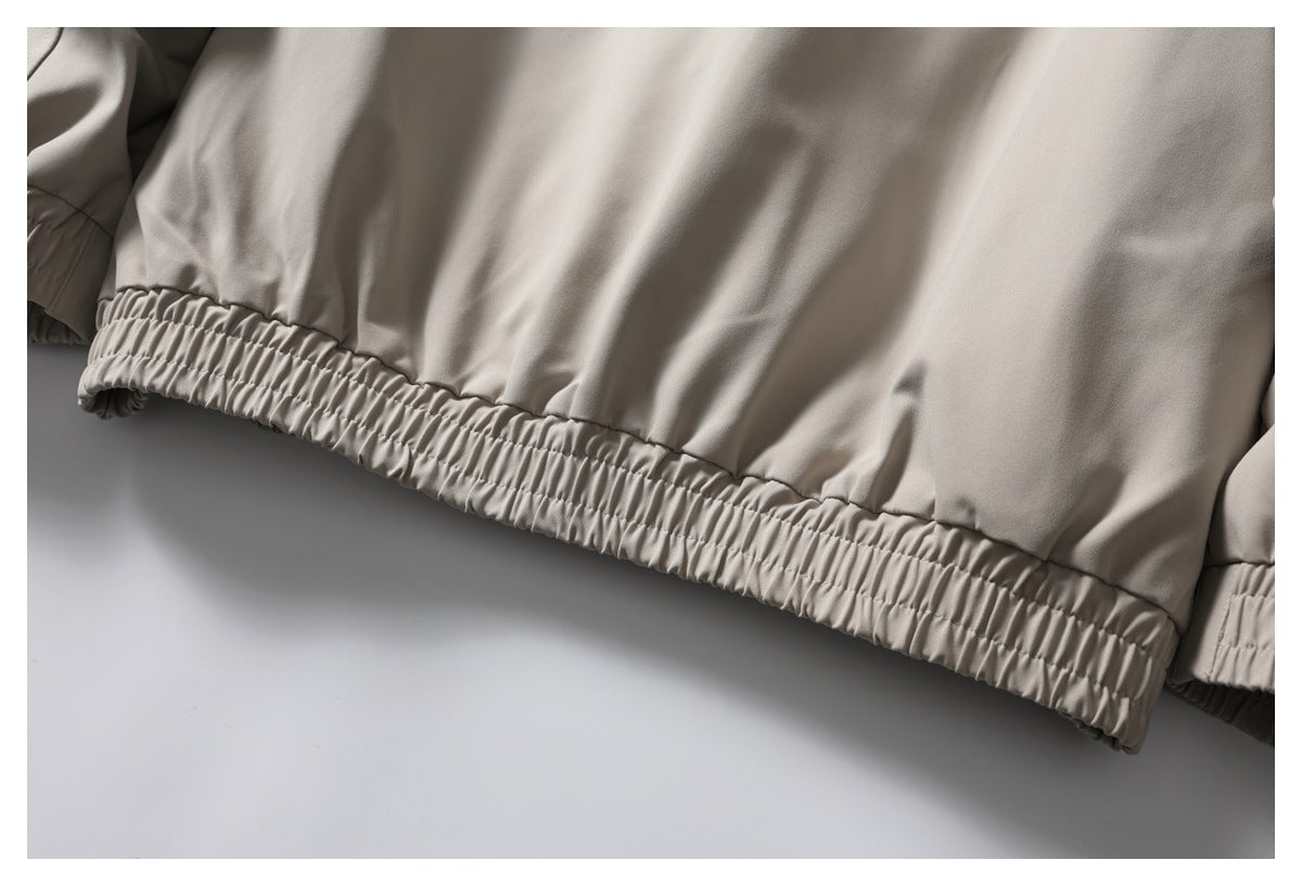 Close-up of a light taupe jacket’s gathered elastic hem.