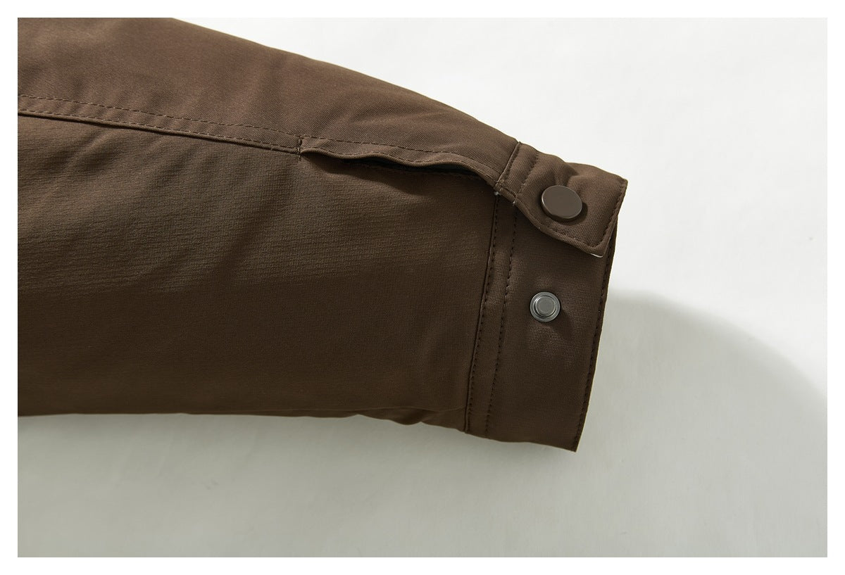 Close-up of a brown jacket sleeve cuff with two snap fasteners and stitched seams.