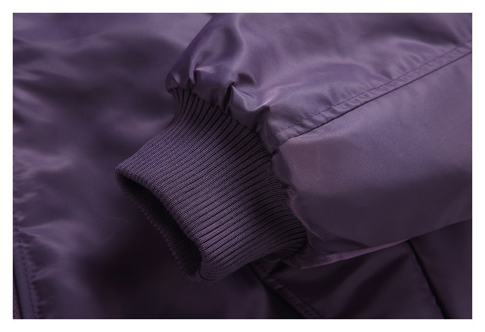 Close-up of a dark purple jacket sleeve with a rib-knit cuff and stitched seam.