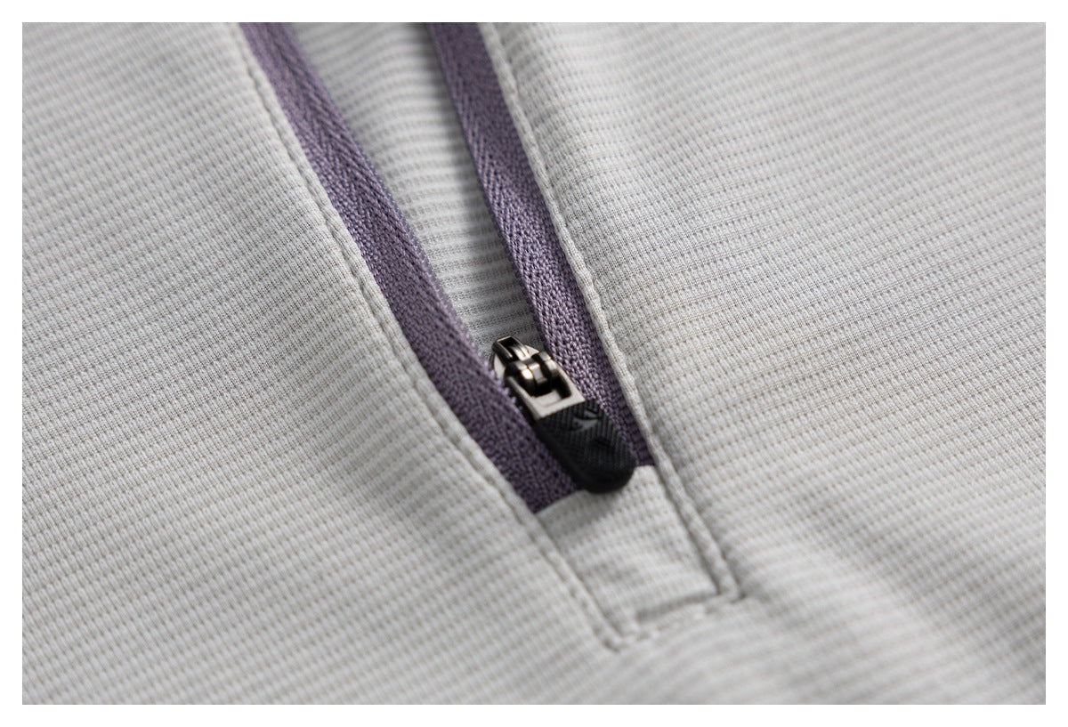 Close-up of a short zipper with lavender tape on the ivory top's fine ribbed fabric.