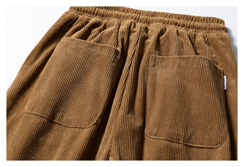 Close view of brown corduroy pants showing an elastic waistband and two large patch pockets.