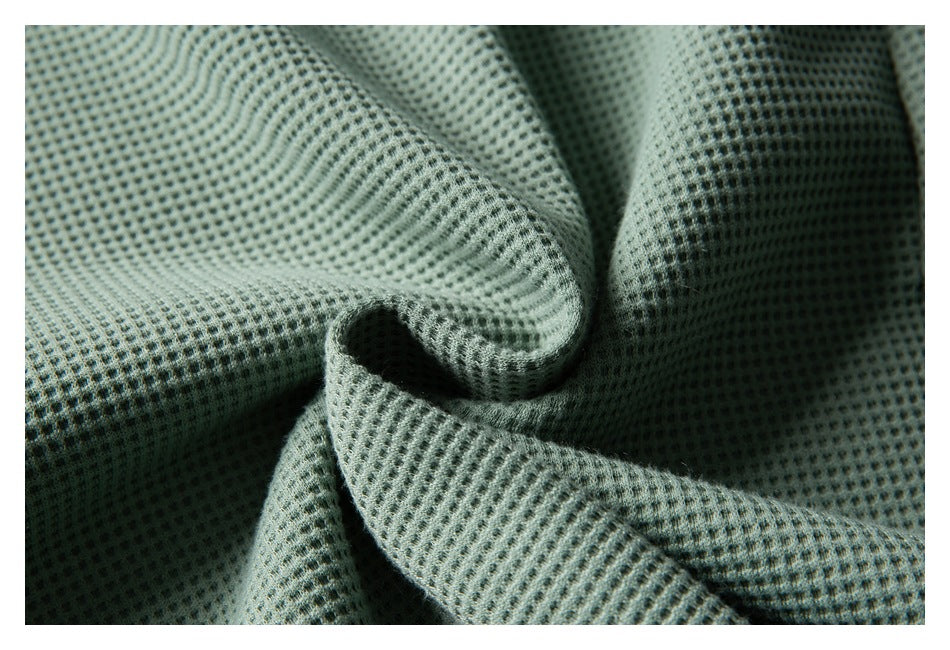 Close-up of sage green textured knit fabric gathered into soft folds.