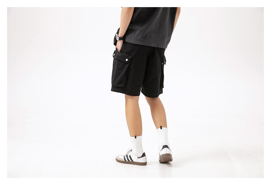Rear three-quarter view of a model wearing black cargo shorts with large flap pockets.