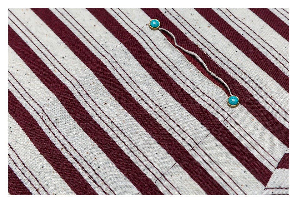 Close-up of cream and burgundy striped fabric with two turquoise buttons on a cord.