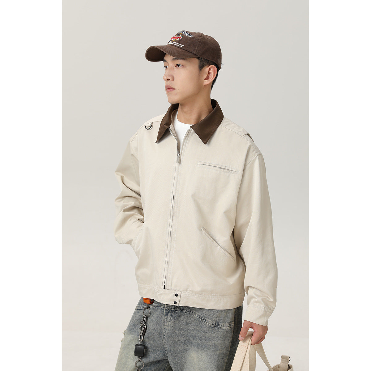 Closer front view of a model in a cream zip-front jacket with a dark brown collar and chest pocket.