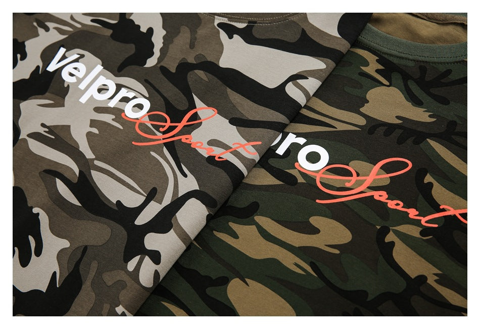 Close-up of tan and green camouflage T-shirts with white lettering and red script printed on the fabric.