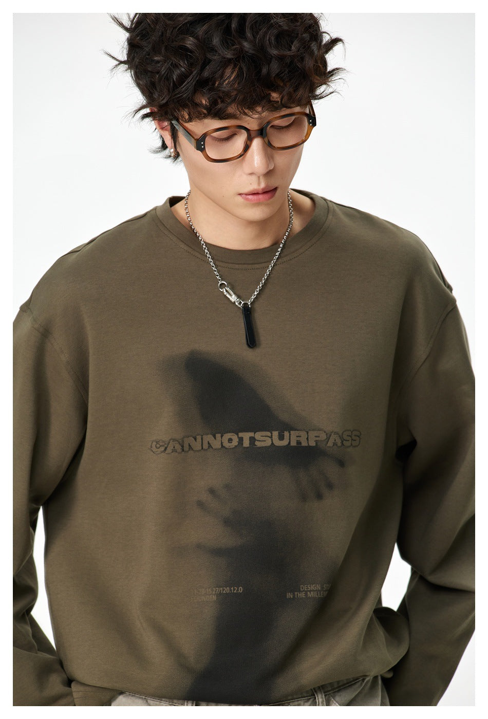 Close view of a model wearing an olive oversized sweatshirt with a dark graphic and text print.