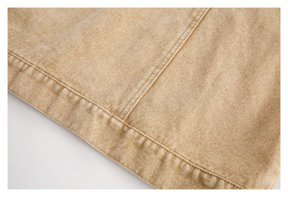 Close-up of the stitched hem and panel seam on tan garment fabric.