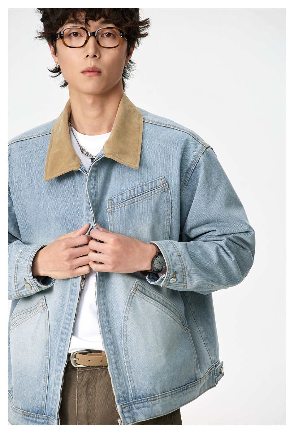 Close view of a light-wash denim jacket showing its tan collar, chest pocket, zip front and cuff details.