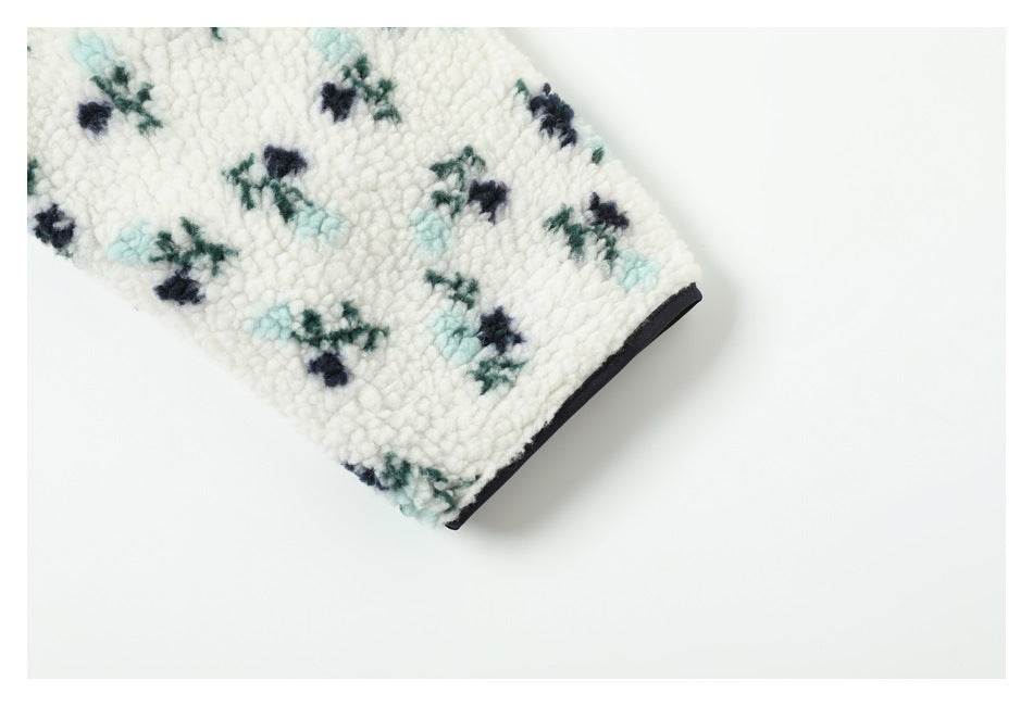 Close-up of an ivory plush sleeve edge with scattered navy, teal, and pale aqua floral motifs and black binding.