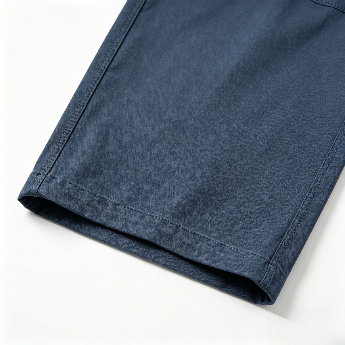 Close-up of a blue trouser leg hem with neat stitching and a folded edge.