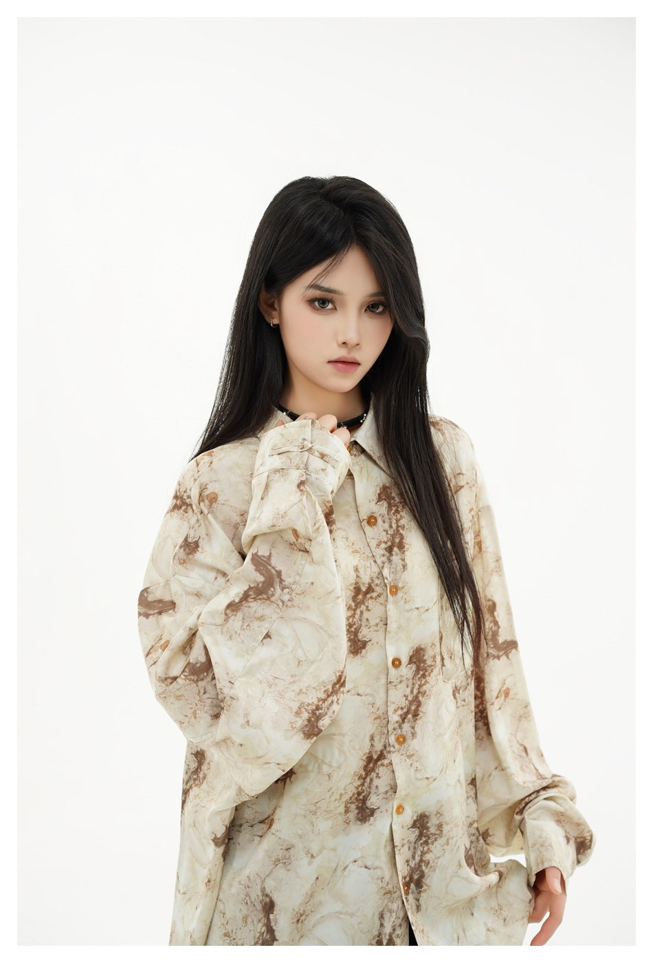 Closer front view of a model wearing an oversized cream and brown marbled button-up shirt.