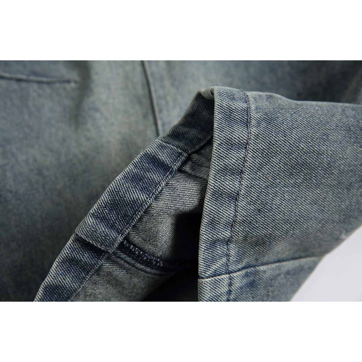 Close-up of the denim shorts' leg opening, hem stitching and inner seam.