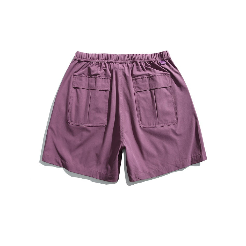 Back view of plum-purple shorts with an elastic waist and two large patch pockets.